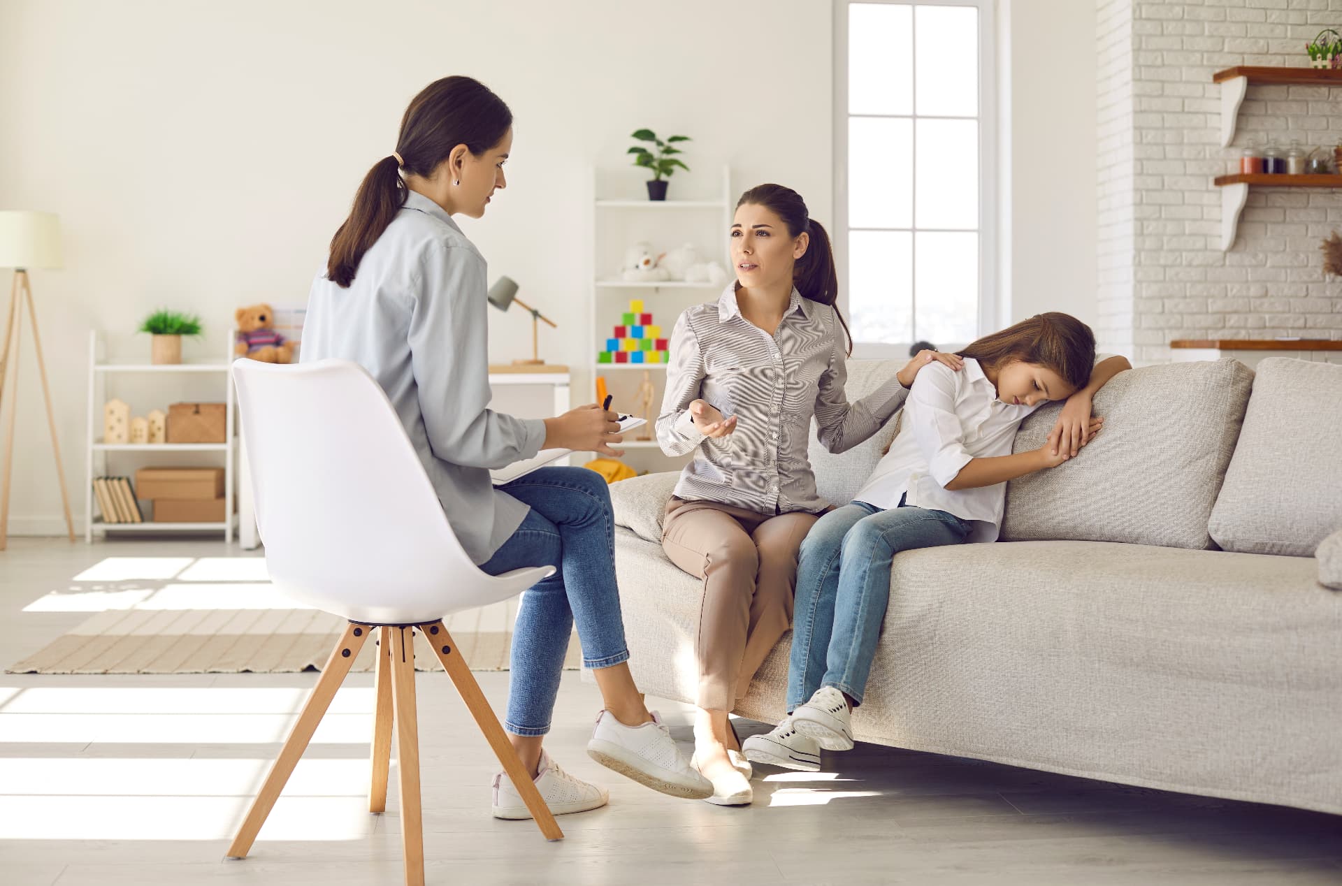 A Quovus clinician meeting with a parent and child in a calm, naturally lit living room