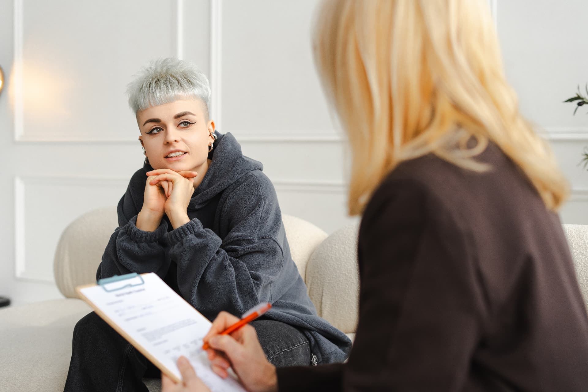 A young person talking with a clinician who is taking notes during a therapy session